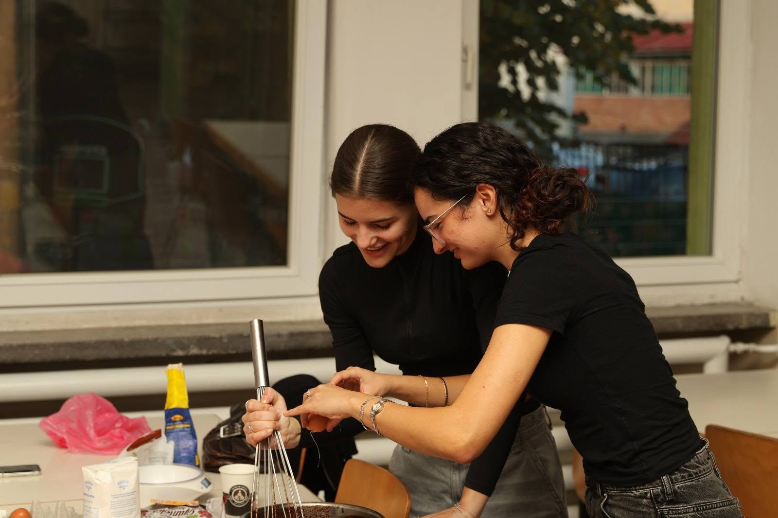 Zwei Schülerinnen lachen und arbeiten zusammen beim Kochabend vor dem Abitur
