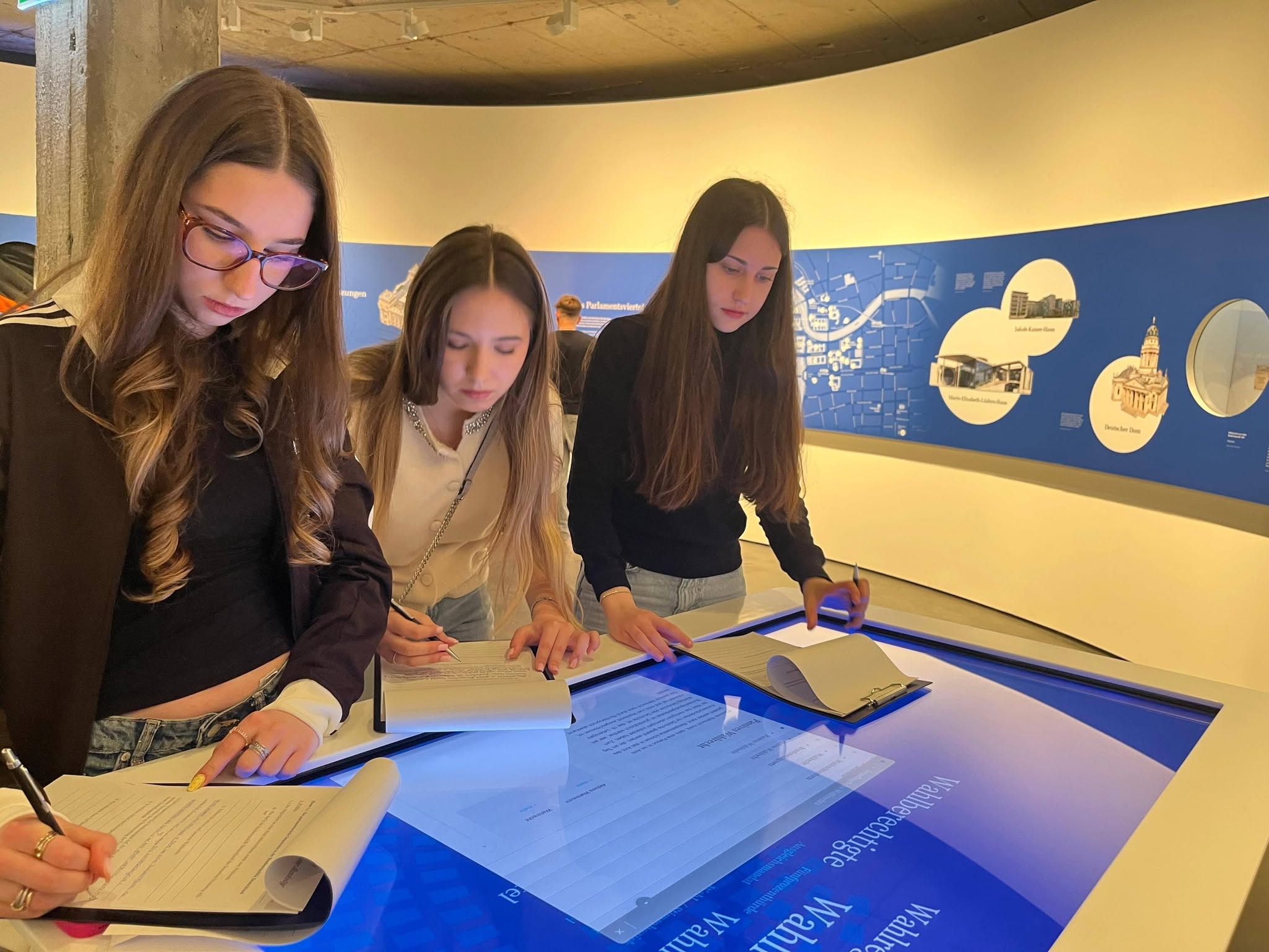 DSA-Schülerinnen bearbeiten Aufgaben an einer Medienstation in der parlamentarhistorischen Ausstellung in Berlin.
